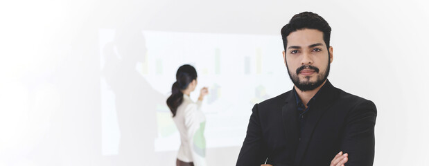 Confident bearded businessman smiling while standing and arms crossed, Businesswoman gives presentation on background, looking at the camera. Banner cover design.