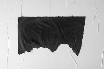 A piece of black crumpled paper taped to a bulletin board.