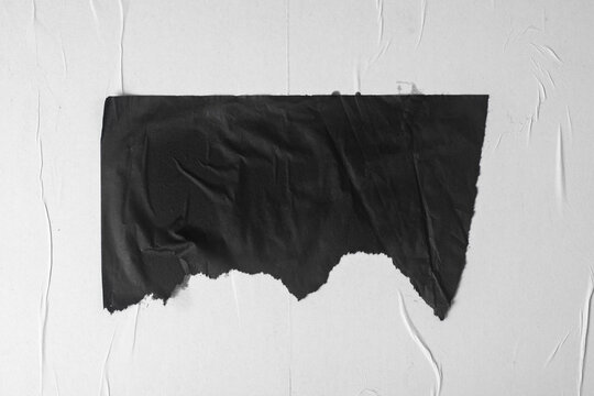 A Piece Of Black Crumpled Paper Taped To A Bulletin Board.