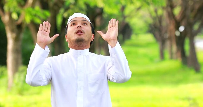 Religious muslim man traditional kandura praying outdoor at quiet nature environment sun beams.