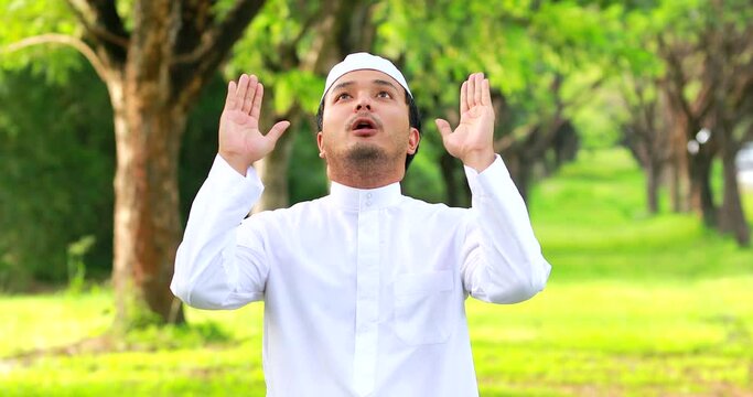 Religious muslim man traditional kandura praying outdoor at quiet nature environment sun beams.