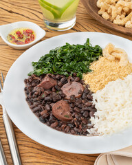Typical brazilian feijoada with rice, pepper, farofa, kale, caipirinha and cracklings