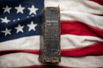 Vintage Christian Holy Bible sitting upright on an antique American flag - 525122685