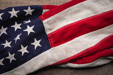 Vintage American flag draped across a rustic wooden background - 525122812