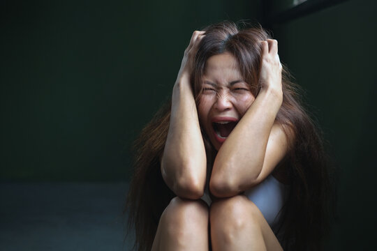 Depressed woman scream and hold her head in stress and pressure.
