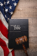 Holy Bible and Gavel resting on an vintage American flag with a rustic wooden background