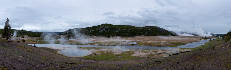Hot spring Geyser with colorful water in American Landscape. Cloudy Sky. Yellowstone National Park, Wyoming, United States. Nature Background Panorama