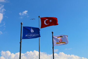 The flag of the Istanbul metropolitan municipality and the maritime flag waving together with the Turkish flag on the pier in Istanbul Eminonu, three side by side