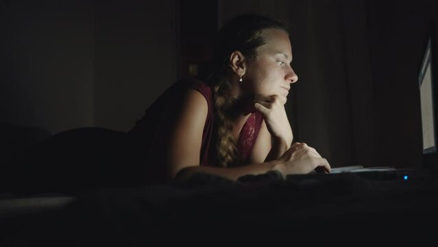 Night, a girl on the bed with a laptop, in motion. Close up