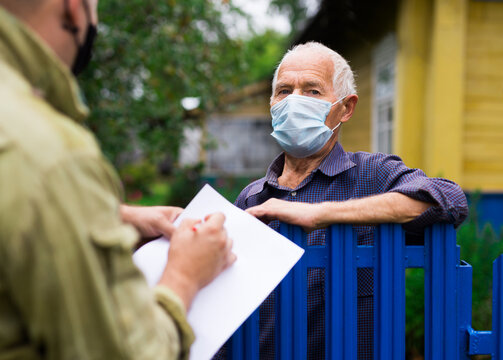 Grandfather In Protective Mask Talking To Census Agent Standing At Fence Of His Country House