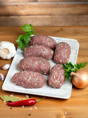 Turkey raw meatballs with vegetables on plate on wooden background.