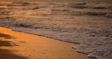 The sandy shore of the Sea of Azov at sunset, a warm summer evening, the waves are beating against the shore, stroking the sand with sea foam, defocus, selective focus.