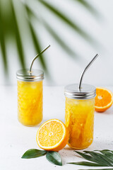 Glasses with orange juice, orange slices and mango on a gray background.