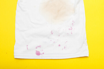 dirty stains on a white T-shirt from berries and drink on yellow background