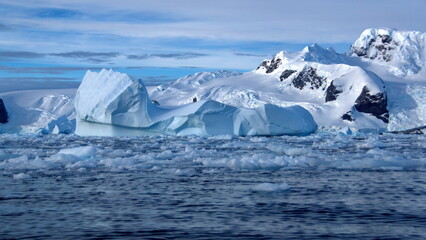 Icebergs floating in the bay, at the base of a snow covered mountain, at Cierva Cove, Antarctica