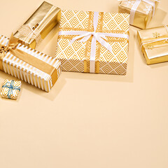 Christmas luxury gift idea. Beautiful minimalist gift box wrapped in paper with golden and white ribbon on a beige background. Christmas, birthday, wedding or another holiday presents preparation.