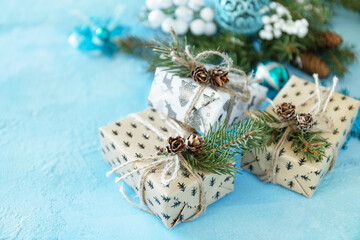 Christmas ornaments and New Year decor. Christmas balls, winter fir tree with present boxs and christmas decor on a blue stone background. Copy space.