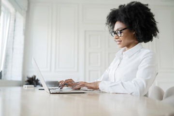 A female secretary in formal attire works in the office answers the client's mail, uses a laptop