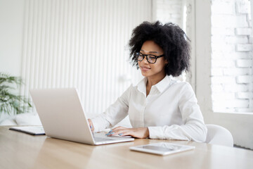 A female receptionist in business clothes works in the office answers the client's mail, uses a laptop