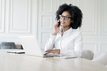 A female secretary with glasses works in the office answers the client's mail, uses a laptop