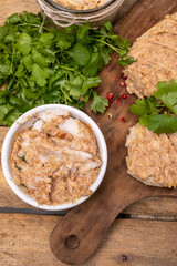 Rillettes, meat pate in a bowl. Rustic composition with spread meat product, fresh herbs and a vintage cutting board. 
