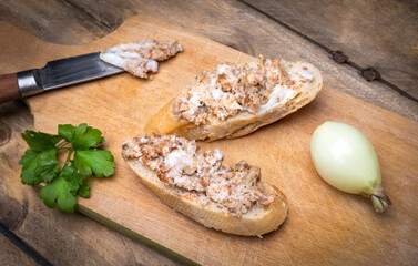 Sandwiches with rillettes, meat pate on a wooden cutting board. Rustic composition with spread meat...