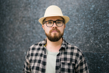 Handsome sad guy tourist wearing straw hat for travelling, standing against concrete wall background