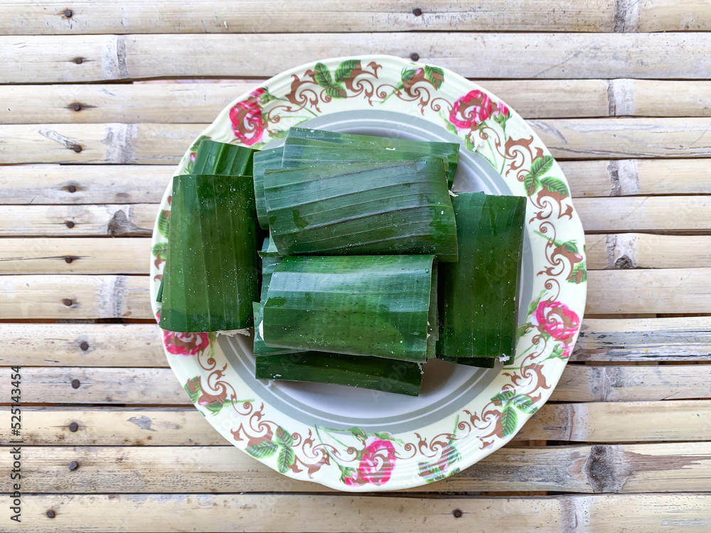 Wall mural A traditional Putu snack from Indonesia, made of glutinous rice, steamed on a bamboo tube and grated coconut as topping then covered with banana leaf.