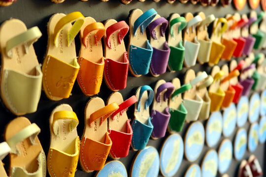 Souvenirs, shaped fridge magnets with small Menorcan avarcas (traditional shoes) - as a symbol of island. Colorful fridge magnets. Selective focus . Ciutadella, Menorca (Minorca), Spain
