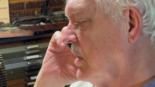 Older man has animated conversation in a letterpress studio.

