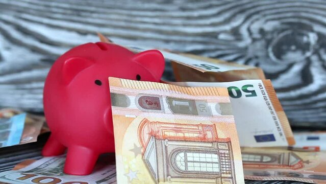 Piggy bank among dollar and euro banknotes. Banknotes fall from above. Multicurrency savings. Risk while saving money.