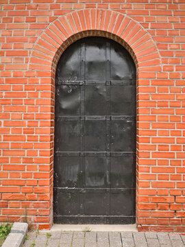 Old metal arch type door in the red brick wall.