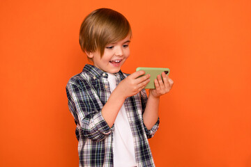 Photo of young cheerful boy race speed addicted play mobile weekend isolated over orange color background