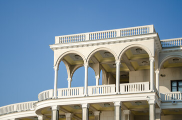 Fototapeta premium facade of the white building with arches and balconies against the background of blue sky