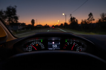 Driver view to the speedometer at 59 kmh or 59 mph, on a road blurred in motion, night fall view...