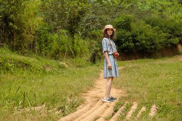 Fototapeta premium Full-length photo of female traveler in hat with photo camera walking around the coffee farm