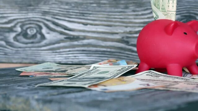 Piggy bank among dollar and euro banknotes. Money sticks out of her. Difficulties in saving money. Multicurrency savings
