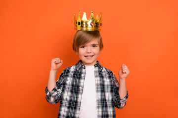 Photo of young excited little boy celebrate luck fists hands prince party isolated over orange...
