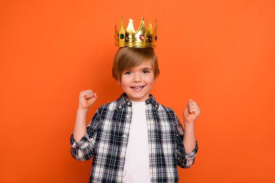 Photo of young excited little boy celebrate luck fists hands prince party isolated over orange color background