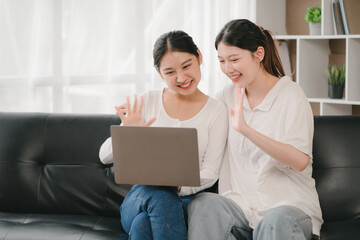 Fototapeta premium Asian woman happy holding laptop phone sitting sofa smiling good mood indoors indoors