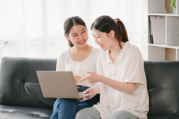 Asian woman happy holding laptop phone sitting sofa smiling good mood indoors indoors