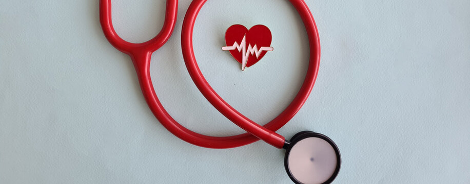 Stethoscope and red heart on light background