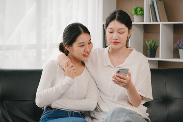 Asian woman happy holding laptop phone sitting sofa smiling good mood indoors indoors