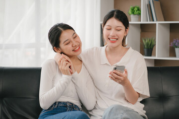 Asian woman happy holding laptop phone sitting sofa smiling good mood indoors indoors