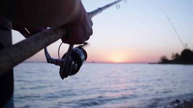 A fishing rod thrown into the sea on sunset sea fishing. The fisherman spins the reel on a spinning rod