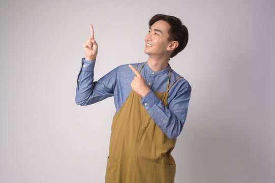 Portrait of young asian man wearing apron over white background studio, cooking and entrepreneur concept