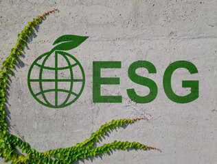 Wall with an inscription ESG Environmental, Social, and Governance and a globe and green leaves.