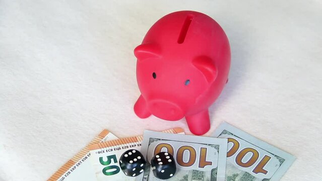 Piggy bank on dollar and euro banknotes. Next to the dice. Multicurrency savings. Risk while saving money