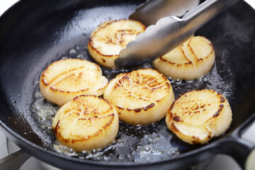 seared scallops in cast iron pan with tongs