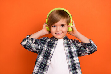Photo of young little boy enjoy listen radio headphones meloman isolated over orange color background